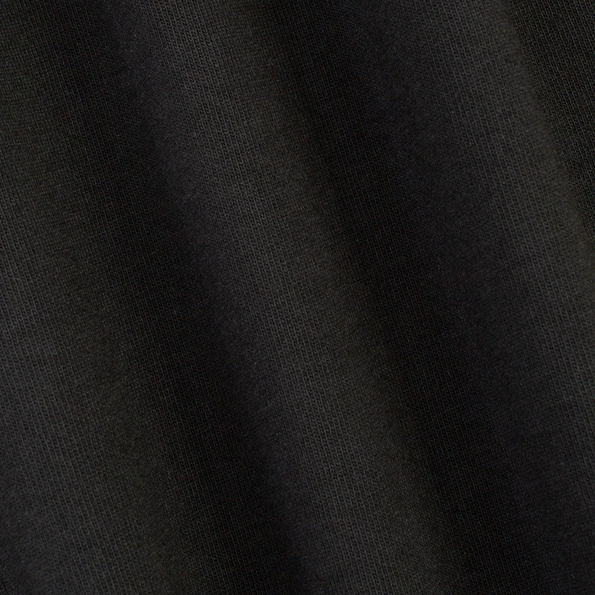 A close-up of dark charcoal gray knit fabric with soft folds showing the fine ribbed texture.